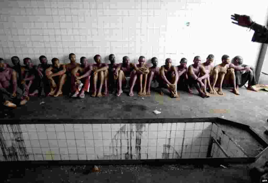 April 6: Men captured by forces loyal to Alassane Ouattara and detained for unknown reasons, sit in the service bay of a gas station near a checkpoint serving as an operating base near a main entrance to Abidjan, Ivory Coast.(AP Photo/Rebecca Blackwell)