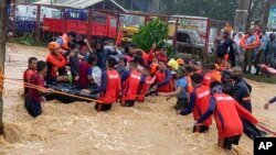 Des secouristes aident des résidents à surmonter les inondations causées par le typhon Rai à Cagayan de Oro City, dans le sud des Philippines, jeudi 16 décembre 2021.