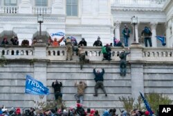 Supporters of President Donald Trump climb the west wall of the the U.S. Capitol on Wednesday, Jan. 6, 2021, in Washington. (AP Photo/Jose Luis Magana)