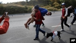 Migrant Darwin Leonel Carcamo is carried by a fellow migrant, part of the caravan hoping to reach the U.S. border, after he fell off a truck and broke his leg, on the road that connects Irapuato with Guadalajara, Mexico, Nov.12, 2018. 