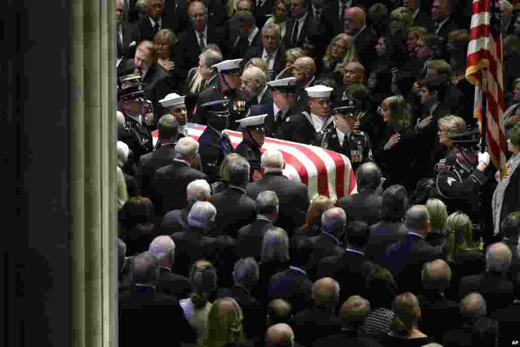 The flag-draped casket of former President George H.W. Bush is carried by a military honor guard during a State Funeral at the National Cathedral, Dec. 5, 2018, in Washington. 