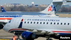 A US Airways Express plane departs from a gate past an American Airlines plane at the Ronald Reagan Washington National Airport in Arlington County, Virginia, February 10, 2013.