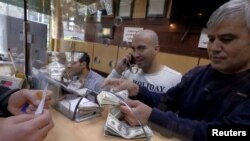 FILE - A currency exchange dealer counts U.S. dollar banknotes at his shop in a shopping center in northern Tehran, Jan. 17, 2016.