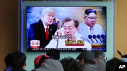 Dân chúng theo dõi màn ảnh truyền hình chiếu ảnh lãnh tụ Triều Tiên Kim Jong Un (bên phải), TT Hàn quốc Moon Jae-in (ở giữa) và TT Mỹ Donald Trump tại trạm xe lửa Seoul, Hàn quốc, ngày 7/3/2018. 