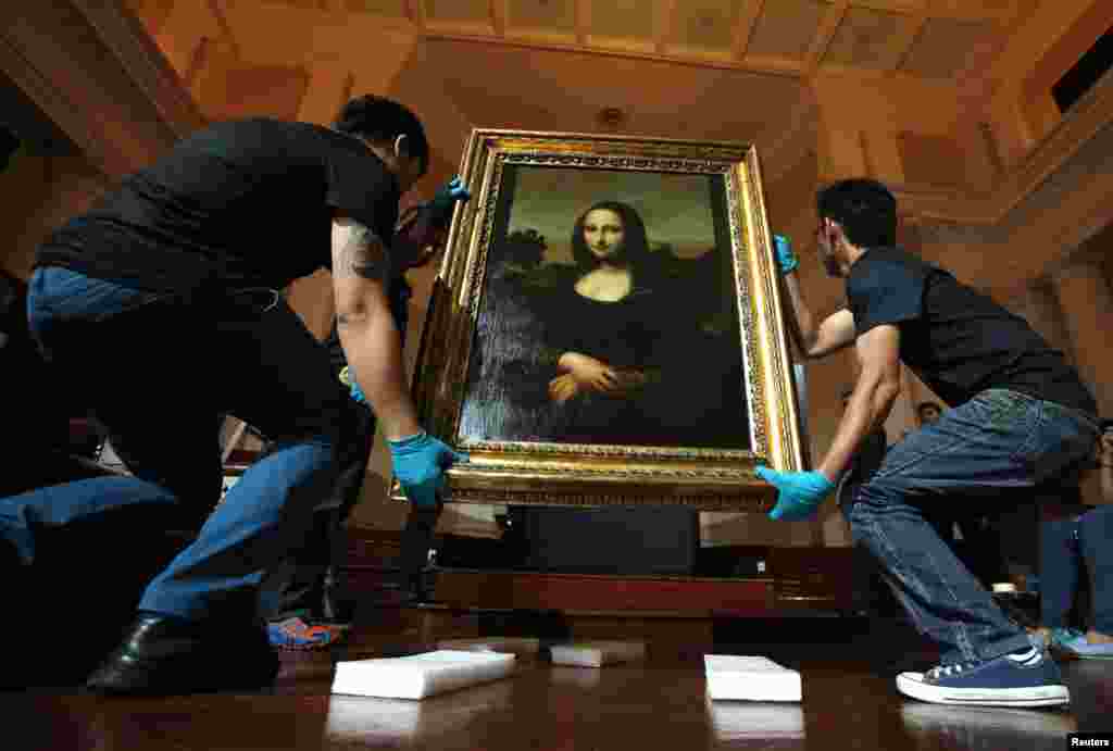 Movers prepare to hang Leonardo da Vinci&#39;s &quot;Earlier Mona Lisa&quot; painting ahead of its exhibition at The Arts House in Singapore. The world premiere of the exhibition will take place from December 16 to February 11, 2015