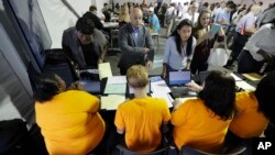 FILE - Job candidates are processed during a job fair at the Amazon fulfillment center in Robbinsville Township, N.J., Aug. 2, 2017. 