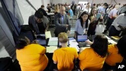 FILE - Job candidates are processed during a job fair at the Amazon fulfillment center in Robbinsville Township, N.J., Aug. 2, 2017.