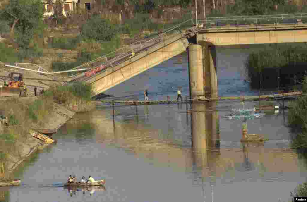 People use a boat to cross the Euphrates River after a bridge was destroyed by shelling, Deir al-Zor, Syria, April 14, 2013. 