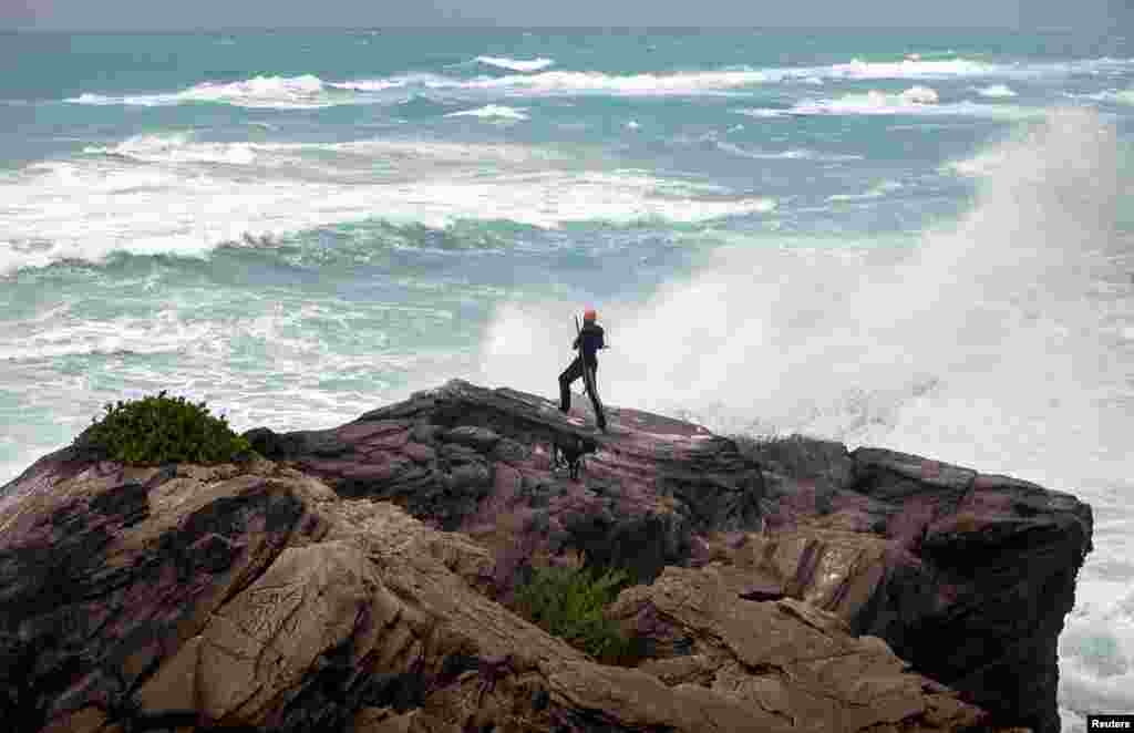A man takes photos while standing on a cliff in Astwood Park, on Bermuda&#39;s south shore, with strong winds blowing from Hurricane Gonzalo. The storm came toward the island with damaging winds and a dangerous surge of water. 