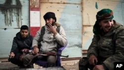 Borci Sirijskih demokratskih snaga (SDF), koje uživaju podršku SAD, sjede ispred zgrade dok se nastavljaju borbe sa militantima Islamske države (IS) u selu Baguz, Sirija, 16. februara 2019.