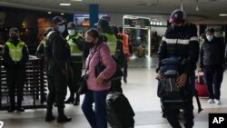 Viajeros llegan al aeropuerto internacional en El Alto, Bolivia, el miércoles 1 de diciembre de 2021, en medio de control policial.