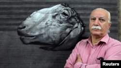 FILE - Syrian painter Youssef Abdelke in front of one of his works at his atelier, Damascus, Sept. 23, 2010.