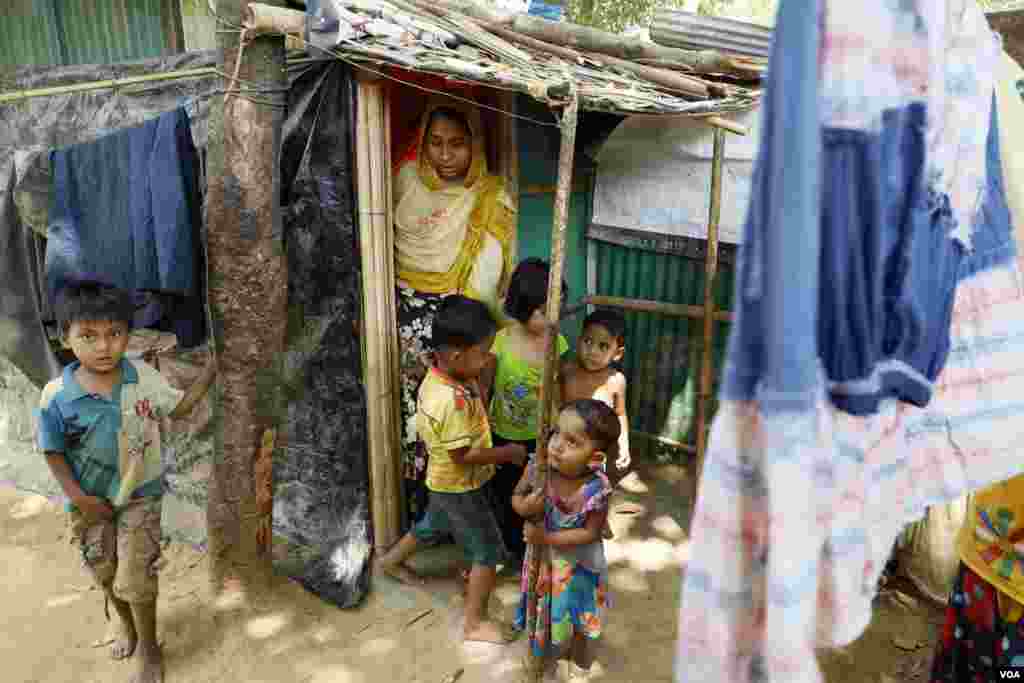 Rohingya refugee Runa and her four children, Aziz, Hazema, Yaseeya and Asiya, emerge from their shelter in the Kutupalong camp Mar. 31, 2019. The shelter kit provided by the UN includes bamboo poles, ropes, plastic cover, and sand bags. (Hai Do/VOA)