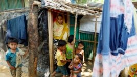 Rohingya refugee Runa and her four children, Aziz, Hazema, Yaseeya and Asiya, emerge from their shelter in the Kutupalong camp Mar. 31, 2019. The shelter kit provided by the UN includes bamboo poles, ropes, plastic cover, and sand bags. (Hai Do/VOA)