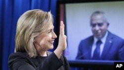 State Secretary Hillary Rodham Clinton waves to Palestinian PM Salam Fayyad, seen on a video monitor, during a video conferencing at the State Department in Washington, announcing the transfer of budget assistance funds to the Palestinian Authority, 10 No