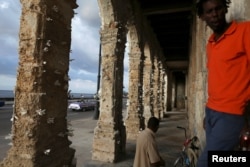 People stand near colonnades decorated with papers by Cuban artist Elio Jesus Fonseca, during the 13th Havana Biennial, in Havana, Cuba, April 12, 2019.
