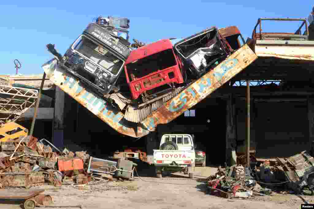 Damaged vehicles pile on a damaged roof of a car mechanic service center in Ramousah area southwest of Aleppo, Syria, August 2, 2016.