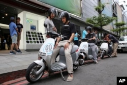 In this Monday, June 15, 2015, photo, Gogoro electric scooters are test driven by potential customers outside a showroom in Taipei, Taiwan.