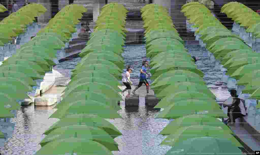 Children walk under umbrellas on display over Cheonggye stream during a campaign to raise money &nbsp;to help underprivileged children in Seoul, South Korea.