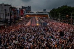 Pro-democracy activists flash three-fingered salutes during a demonstration at Kaset intersection, suburbs of Bangkok, Thailand, Monday, Oct. 19, 2020. Thai authorities worked Monday to stem a growing tide of protests calling for the prime minister to res