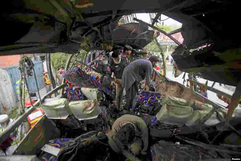 Police and rescue personnel search a bus damaged in a bomb blast, which killed at least 15 people, in Peshawar, Pakistan.