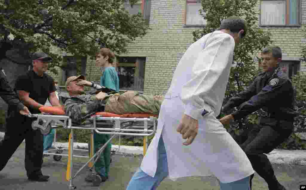Ukrainian soldiers and a doctor carry a wounded soldier in a hospital in Izyum close to Slovyansk, Ukraine, June 3, 2014.