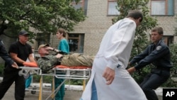 Ukrainian soldiers and a doctor carry a wounded soldier in a hospital in Izyum close to Slovyansk, Ukraine, June 3, 2014.