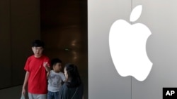 FILE - A Chinese family walks out of an Apple store in Beijing, July 30, 2017.Hundreds of workers protested Wednesday night, Oct. 18, 2017, over bonuses promised through labor brokers who recruited them to work at Jabil Inc.'s Green Point factory, an Apple supplier, in Wuxi city in southern China, according to witnesses.