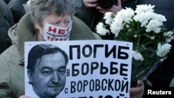 FILE - A woman holds a placard with a portrait of Sergei Magnitsky during an unauthorized rally in central Moscow, Dec. 15, 2012. The placard reads "Died fighting a system of thievery."