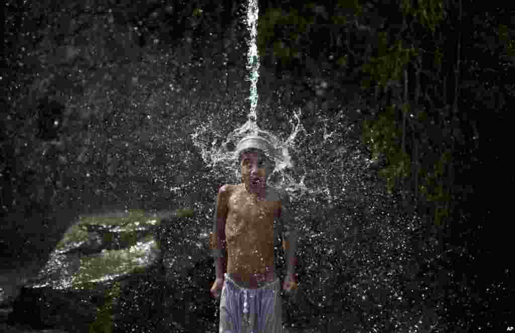 A Pakistani boy reacts to the cold water as he showers himself with leaking water from a supply pipe in Islamabad.