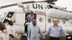 A member of the joint U.N. African Union Mission in Darfur (UNAMID), right, escorts three freed humanitarian workers out of a U.N. helicopter as they landed in El Fasher, North Darfur, Sudan, Saturday, July 19, 2014. 