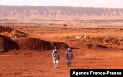 A couple of astronauts from a team from Europe and Israel walk in spacesuits during a training mission for planet Mars at a site that simulates an off-site station at the Ramon Crater in Mitzpe Ramon in Israel's southern Negev desert on October 10, 2021.