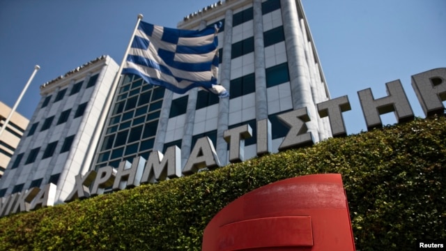 Una bandera griega ondea frente al edificio de la Bolsa de Valores de Atenas, Grecia.