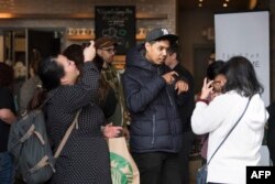 Para pengunjung berbincang menggunakan bahasa isyarat di kafe Starbucks yang pertama mempekerjakan karyawan penyandang tuna rungu atau mengalami kesulitan pendengaran, di Washington DC, 23 Oktober 2018. Para pelayan di kafe tersebut berkomunikasi dengan pelanggan menggunakan bahasa isyarat Amerika.