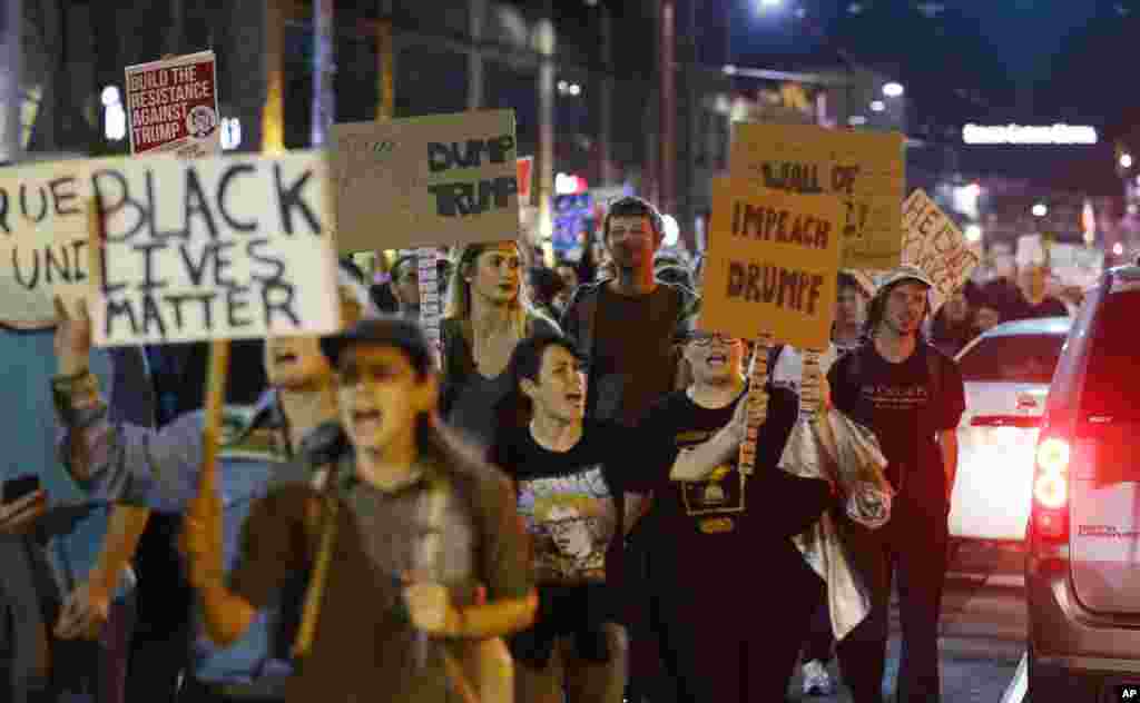 Protesters hold signs during a protest against the election of President-elect Donald Trump, in downtown Seattle, Nov. 9, 2016.