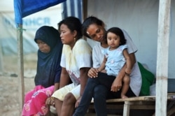 Ibu-ibu dan seorang anak perempuan duduk di depan tenda merea di hunian sementara di Palu, Sulawesi Tengah, 25 September 2019. (Foto: AFP)