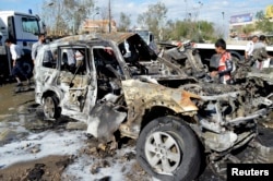 Iraqi security forces and civilians gather at the site of a car bomb attack in Baghdad, Oct. 21, 2014.