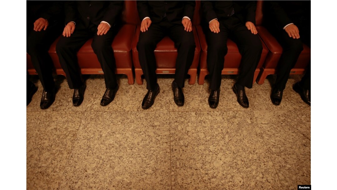 FILE - Security agents wear black as they sit on chairs inside the Great Hall of the People, where sessions of the National People's Congress and the Chinese People's Political Consultative Conference take place, in Beijing, China, March 5, 2016.