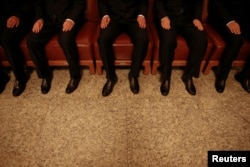 FILE - Security agents wear black as they sit on chairs inside the Great Hall of the People, where sessions of the National People's Congress and the Chinese People's Political Consultative Conference take place, in Beijing, China, March 5, 2016.