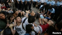 Protesters join hands as they look at fellow protesters being dragged away by the police in Hong Kong's financial Central district after staging an overnight sit-in, July 2, 2014.