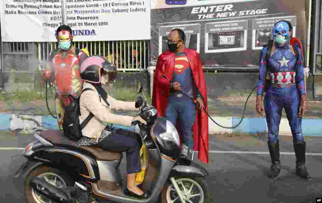 Police officers in superhero costumes spray disinfectant on motorists passing by during a coronavirus awareness campaign on a street in Pasuruan, East Java, Indonesia.