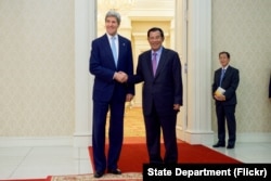 ລມຕ. ການຕ່າງປະເທດສະຫະລັດ ທ່ານ John Kerry ຢືນຖ່າຍຮູບກັບ ນາຍົກລັດຖະມົນຕີ Hun Sen ແຫ່ງກຳປູເຈຍ ທີ່ພົບປະກັນໃນກອງປະຊຸມການຄ້າສອງຝ່າຍ, 26 ມັງກອນ 2016, ໃນພະລາດຊະວັງສັນຕິພາບ, ພະນົມເປັນ, ກຳປູເຈຍ.