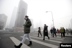 FILE - A man wearing a respiratory protection mask walks toward an office building during the smog after a red alert was issued for heavy air pollution in Beijing's central business district, China, Dec. 21, 2016.