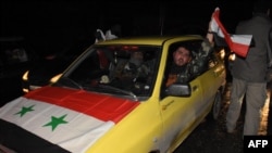 A Syrian driver flies a national flag as people celebrate in the streets in Aleppo, Syria, after the army said it had retaken full control of the city, Dec. 22, 2016. The victory against opposition forces was the army's biggest since the civil war erupted in 2011.