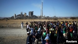 Miners chant slogans as they march past the Lonmin mine during the one-year anniversary commemorations to mark the killings of 34 striking platinum miners shot dead by police outside the Marikana platinum mine in Rustenburg, Aug. 16, 2013.