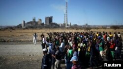 FILE - Miners chant slogans as they march past the Lonmin mine during the one-year anniversary commemorations to mark the killings of 34 striking platinum miners shot dead by police outside the Marikana platinum mine in Rustenburg, South Africa on Aug. 16, 2013.