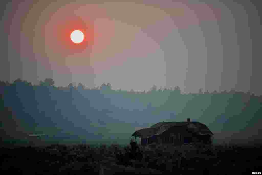 Thick smoke causes the sun to glow red over an abandoned farmhouse as the Bootleg Fire expands to over 200,000 acres, near Beatty, Oregon, July 13, 2021.