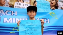 FILE - A Vietnamese boy holds a banner during a rally denouncing recent mass fish deaths in Vietnam's central province, in Hanoi, Vietnam, May 1, 2016. Tho show their solidarity, Taiwan-based Vietnamese workers took to the streets of Taipei on Monday.