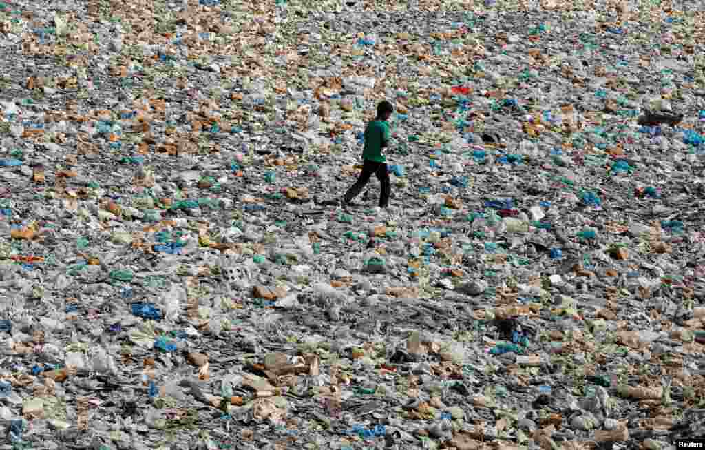 A boy walks over a drainage channel littered with heaps of polyethene bags in Karachi, Pakistan.