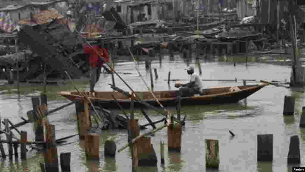 A man paddles a canoe past illegal stilt houses in Legas that are at risk of being demolished by the government.